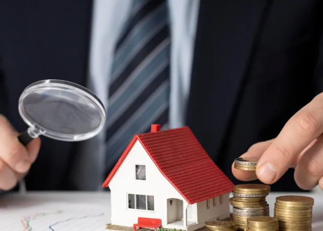 A model house, stacked coins and a magnifying glass, showing how a property is valued for a loan